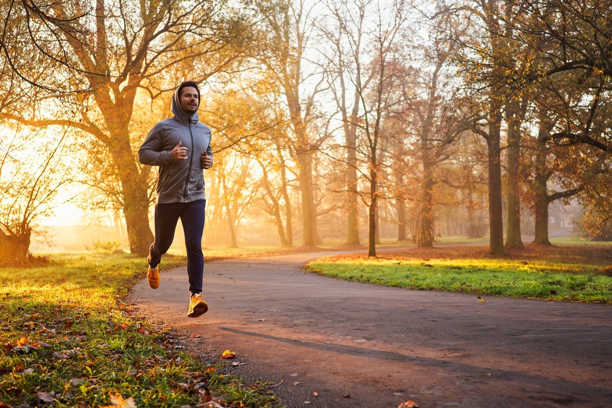 Adult male runner in park at autumn sunrise