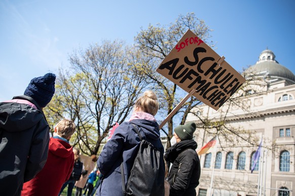 Eine Frau hält während einer Demonstration unter dem Motto „Homeschooling-Streik“ von Eltern und Kindern vor der bayerischen Staatskanzlei ein Schild mit der Aufschrift „Sofort Schulen aufmachen“ in d ...