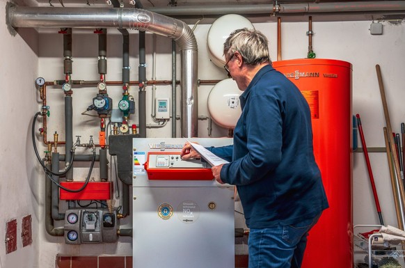 Ein Rentner kontrolliert seine Gasheizung mit Warmwasserspeicher.