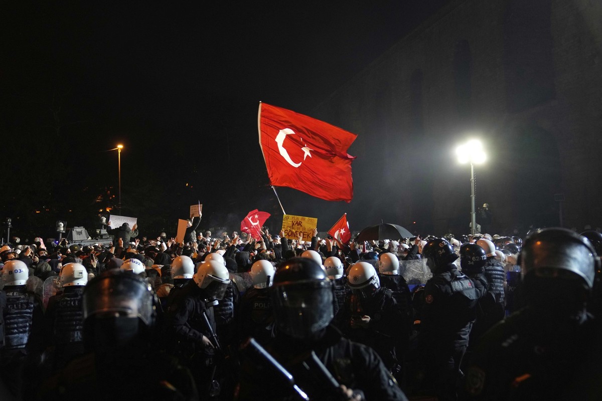 24.03.2025, Türkei, Istanbul: Menschen nehmen neben Polizisten an einer Demonstration teil, nachdem der Bürgermeister von Istanbul, Imamoglu, festgenommen und inhaftiert wurde. Foto: Khalil Hamra/AP/d ...
