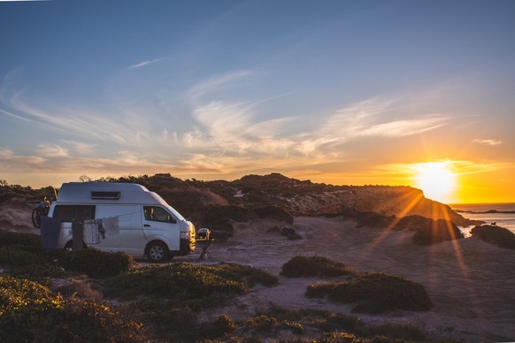 Camping on a cliff edge in a camper van, beautiful sunset landscape