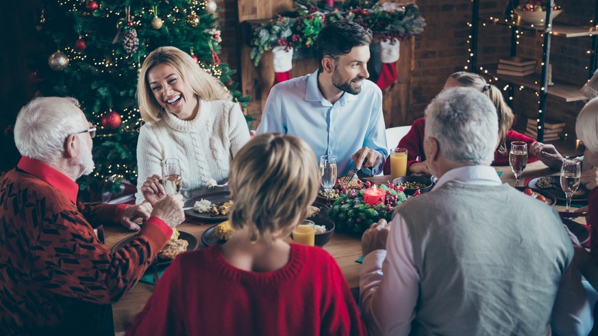 Photo of full family gathering sitting dinner table communicating chatting overjoyed x-mas party multi-generation in newyear decorated living room indoors