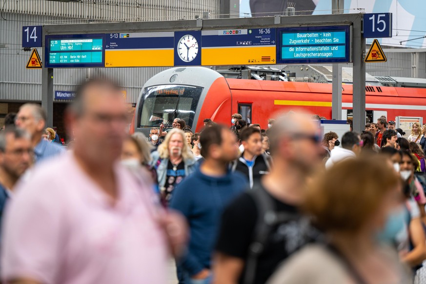 Reisende gehen am Hauptbahnhof in München durch die Bahnhofshalle.