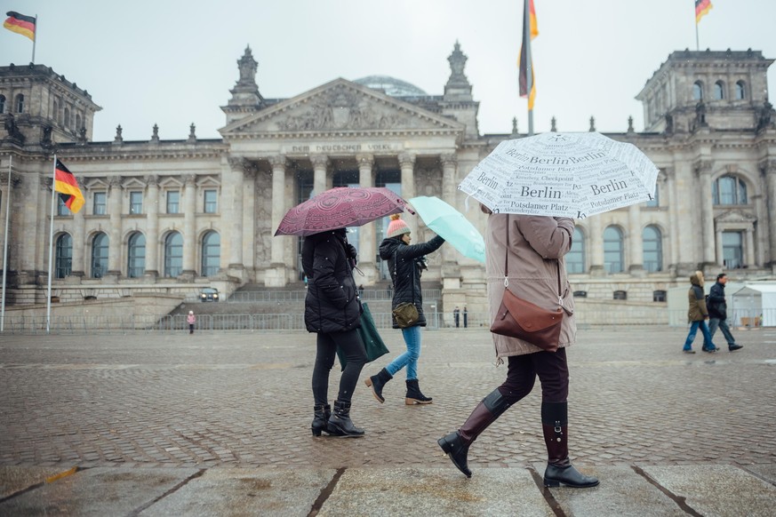 ARCHIV - 28.03.2018, Berlin: Touristen halten bei nasskaltem Wetter Regenschirme in den H