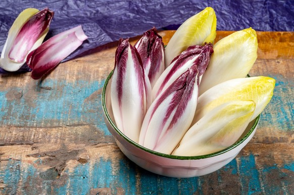 Fresh organic Belgian endivi or green and red chicory lettuce close up in bowl