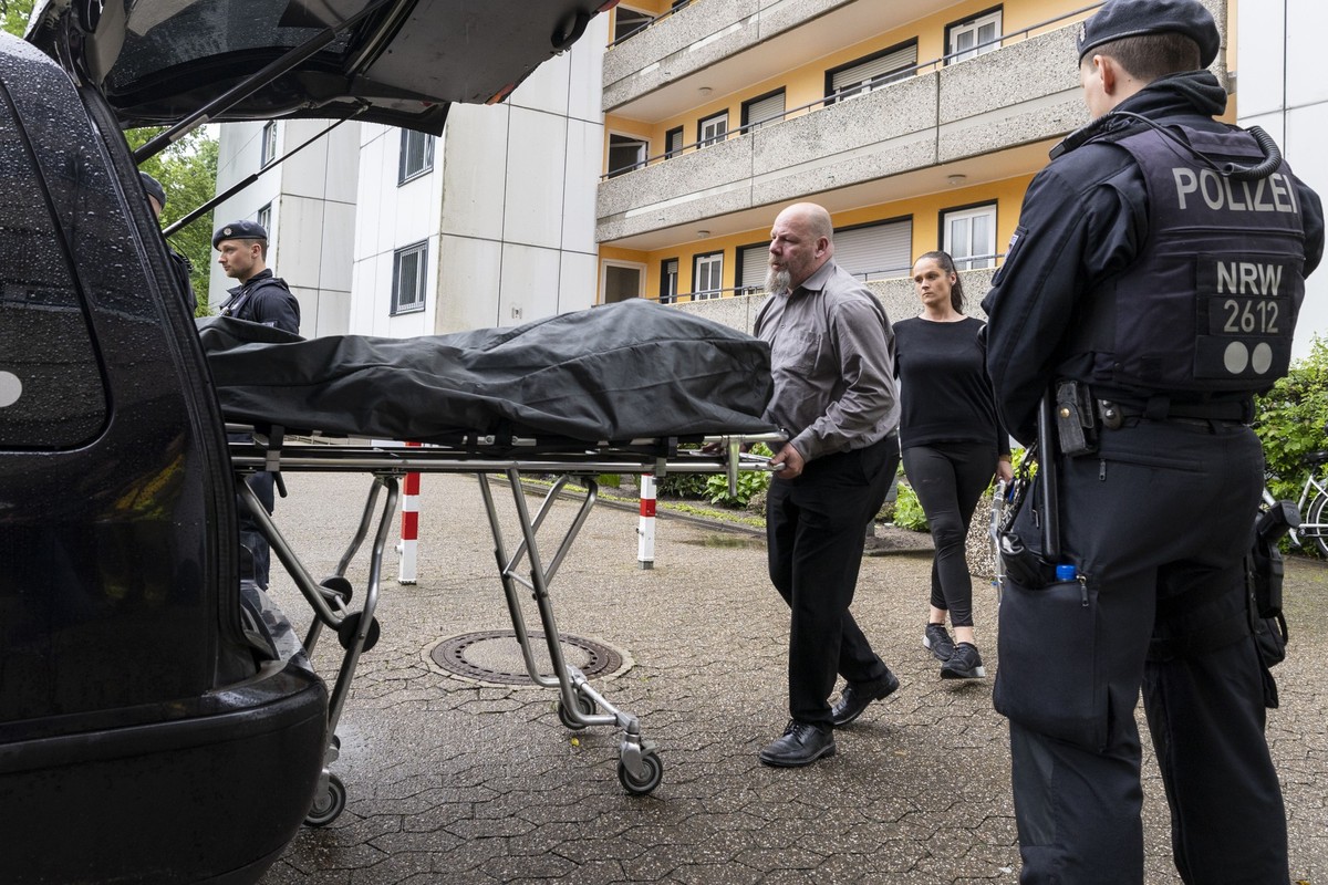 11.05.2023, Nordrhein-Westfalen, Ratingen: Bestatter bringen den Leichnam einer in einer Wohnung aufgefundenen Person zum Leichenwagen. Einsatzkr�fte der Polizei stehen neben dem Auto. Nach der Explos ...