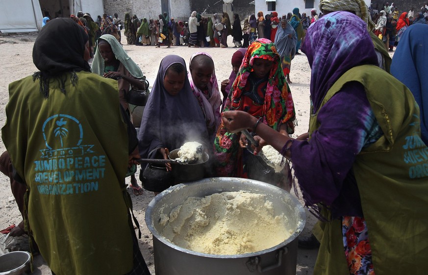MOGADISHU, SOMALIA - AUGUST 14: Women and children receive food aid on August 14, 2011 in Mogadishu, Somalia. A local Somali agency distributes cooked porridge from World Food Progam to hundreds of wo ...