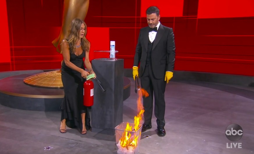 In this video grab captured on Sept. 20, 2020, courtesy of the Academy of Television Arts &amp; Sciences and ABC Entertainment, Jennifer Aniston, left, and Jimmy Kimmel sanitize the winner's envelope  ...