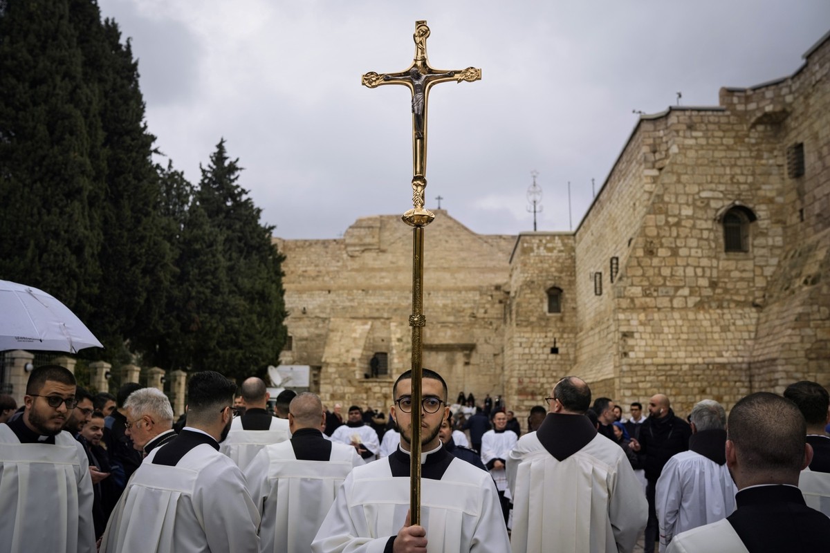 dpatopbilder - 24.12.2023, Palästinensische Gebiete, Bethlehem: Katholische Geistliche gehen am Heiligabend in der Stadt Bethlehem im Westjordanland in einer Prozession neben der Geburtskirche, die tr ...