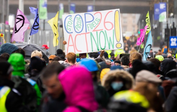 Ein Plakat für besseren Klimaschutz wird bei einem Protest vor dem Gelände der UN-Klimakonferenz COP26 in die Höhe gehalten. In Glasgow ringen rund 200 Staaten für zwei Wochen darum, wie das Ziel, die ...