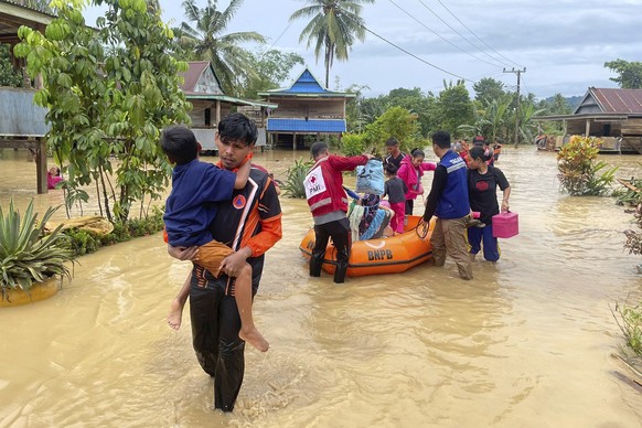 HANDOUT - 03.05.2024, Indonesien, Wajo: Auf diesem von der regionalen Katastrophenschutzbehörde von Wajo (BPBD Wajo) veröffentlichten Bild tragen Rettungskräfte Menschen, die von einer Überschwemmung  ...