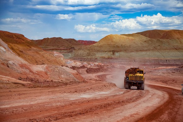 Arkalyk/Kazakhstan - May 15 2012: Aluminium ore mining and transporting. Bauxite clay mine. Heaps of empty ground. Cargo truck &quot;Belaz&quot; on red clay road. Blue sky with clouds.