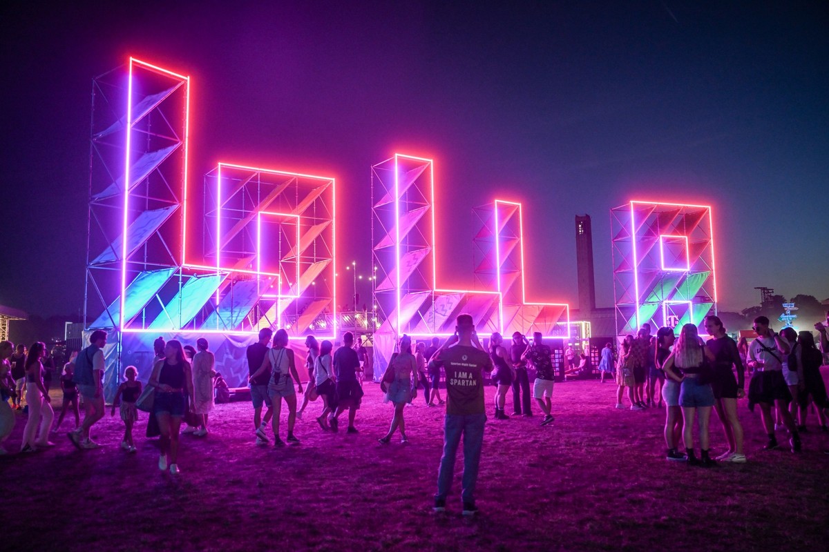 09.09.2023, Berlin: Besucher gehen beim Lollapalooza Festival Berlin auf dem Gelände des Olympiastadions an illuminierten Buchstaben mit dem Schriftzug &quot;Lolla&quot; vorbei. Foto: Britta Pedersen/ ...