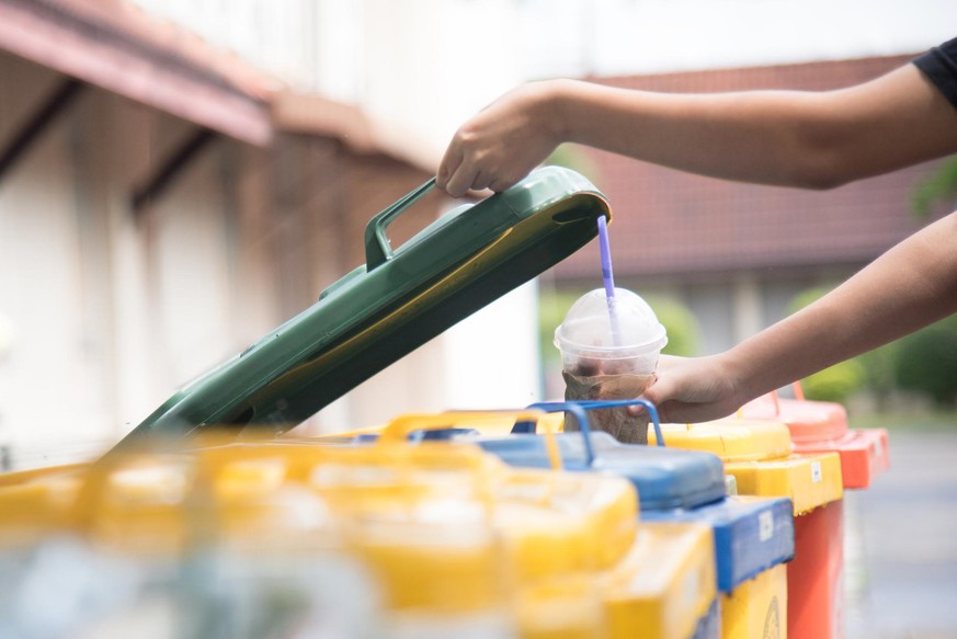 children hand throwing empty plastic bottle into the trash.saving environment by throwing plastic jung in to the recycle bin or garbage