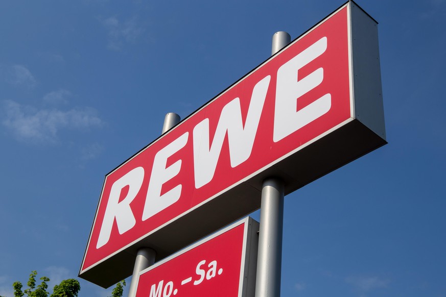 Logo von der Einzelhandelskette REWE vor blauem Himmel