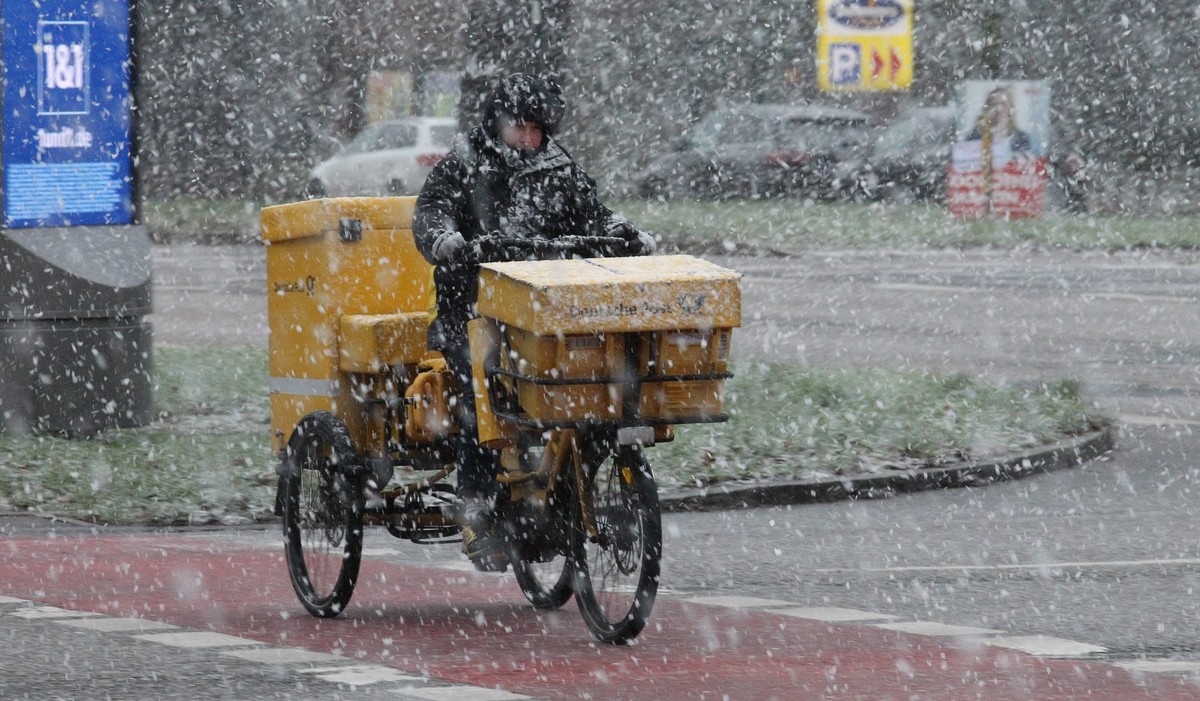 Wintereinbruch in Hamburg. Am Freitagvormittag gab es phasenweise heftigen Schneefall in der Hansestadt. Ein Briefzusteller Postbote der Deutschen Post passiert die Kreuzung Wiesendamm/Saarlandstra