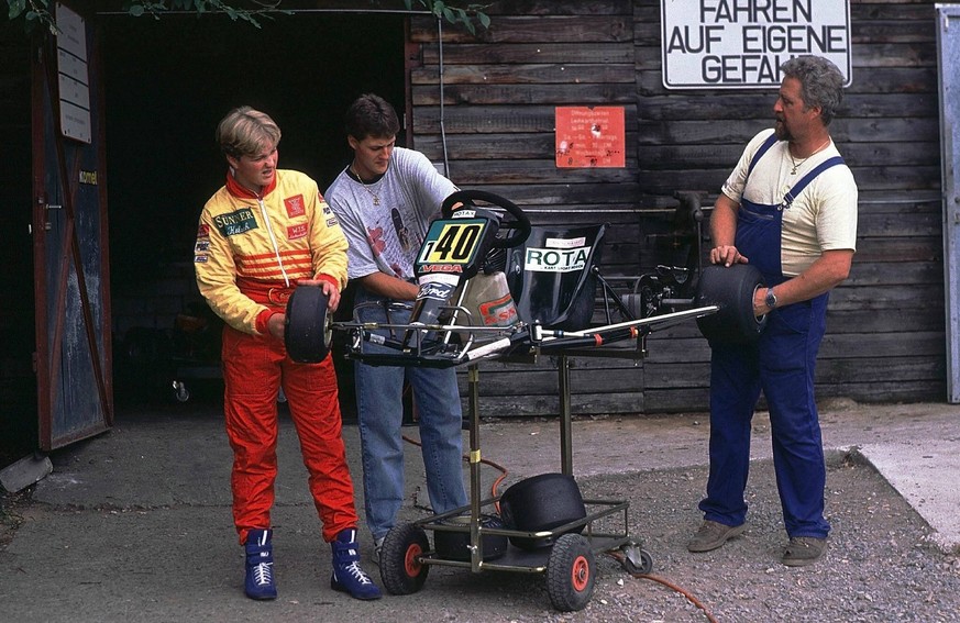 Michael Schumacher (Mitte), Bruder Ralf Schumacher (li.) und Vater Rolf schrauben an einem Gokart.