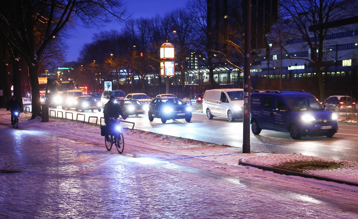 17.01.2024, Hamburg: Radfahrer sind auf einem vereisten Radweg neben einer Hauptverkehrsstra