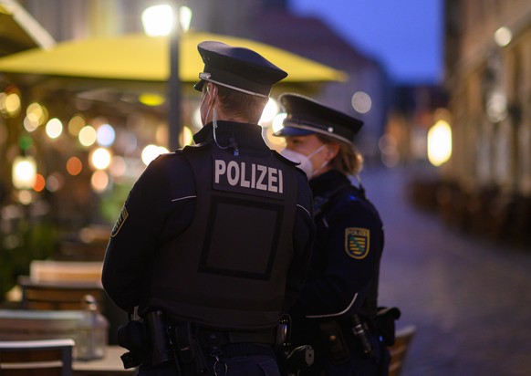 Polizisten stehen am Abend in der Dresdner Altstadt vor einem Restaurant. Die Polizeidirektion Dresden kontrolliert die Einhaltung der neuen Corona-Regeln täglich mit 50 Beamtinnen und Beamten. Im Fok ...