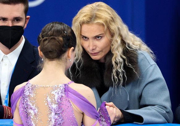 BEIJING, CHINA - FEBRUARY 15, 2022: ROC figure skater Kamila Valieva front approaches her coaches Daniil Gleikhengauz L back and Eteri Tutberidze during the women s short programme event at the Capita ...