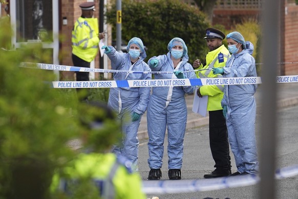 Forensics officers gesture near the scene of an attack in Hainault, north east London, Tuesday April 30, 2024. A man wielding a sword attacked members of the public and police officers in a east Londo ...