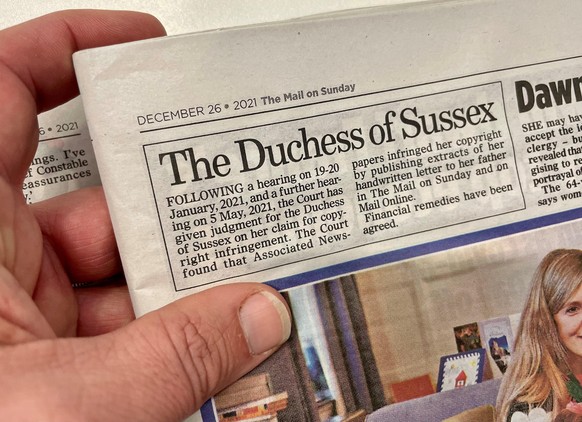 Duchess of Sussex court case. A man holds a copy of the Mail on Sunday with a printed a statement on page three acknowledging that the Duchess of Sussex won her copyright claim against the newspaper's ...