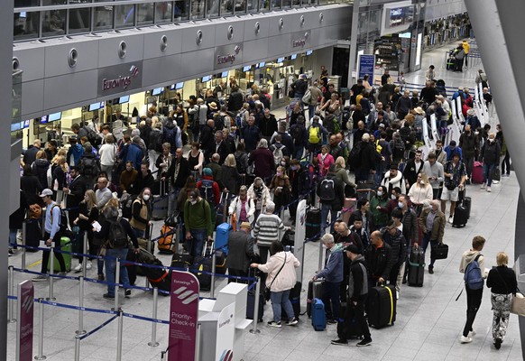 17.10.2022, Nordrhein-Westfalen, Düsseldorf: Reisende stehen am Eurowings Check-In-Schalter Schlange. Am Flughafen Düsseldorf fallen viele Starts von Flugzeugen der Airline aus, weil deren Piloten für ...