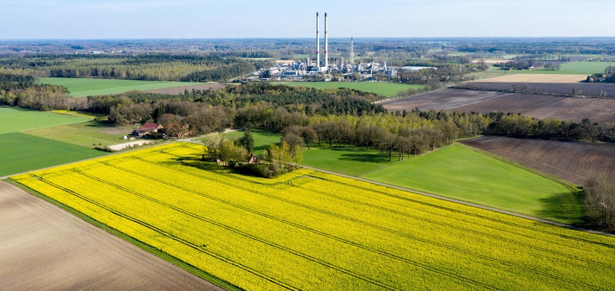 15.04.2020, Niedersachsen, Grossenkneten: Raps blueht im Ortsteil Sage auf einem Feld (Luftaufnahme mit Drohne). Im Hintergrund ist die Erdgasaufbereitungsanlage (EAA) von ExxonMobil zu erkennen. Foto ...