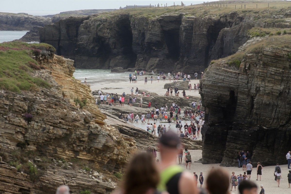 28.07.2022, Spanien, Lugo: Touristen besuchen den Strand Las Catedrales in Galicien. Pro Tag d