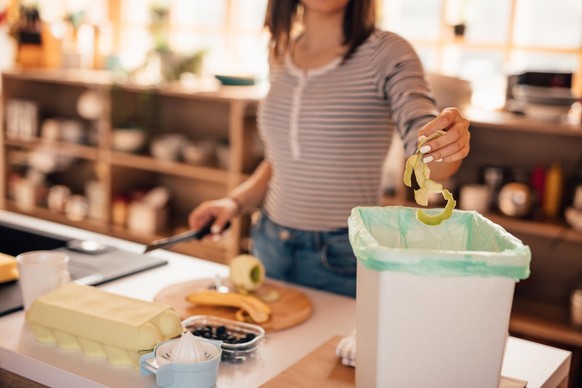 Millennial woman putting organic waste in compost bin