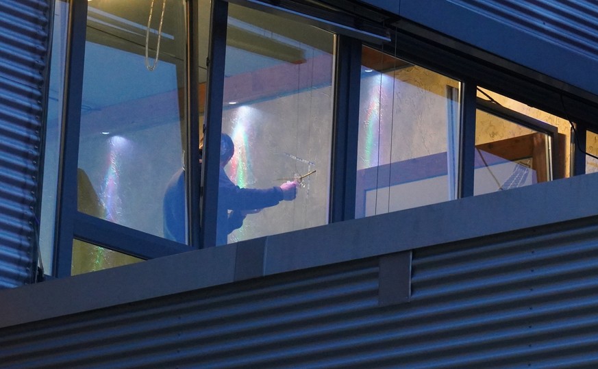 Ermittler untersucht ein Einschussloch in einer Fensterscheibe.Unbekannte haben in Stuttgart auf das Fenster einer Shisha-Bar geschossen.