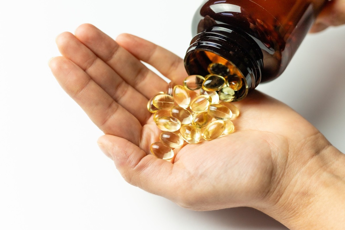 Vitamin D3 capsules poured out of the package. Care for health and immunity. A woman&#039;s hand.