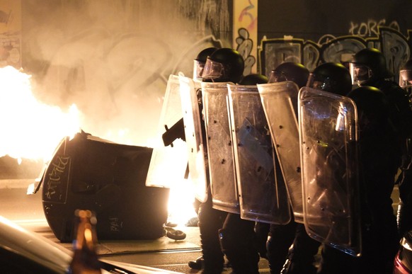 02.06.2023, Sachsen, Leipzig: Polizisten stehen an einem brennenden Conatainer und schützen sich vor Bewurf. Am Freitagabend ist es im Stadtteil Connewitz zu Ausschreitungen gekommen. Foto: Sebastian  ...