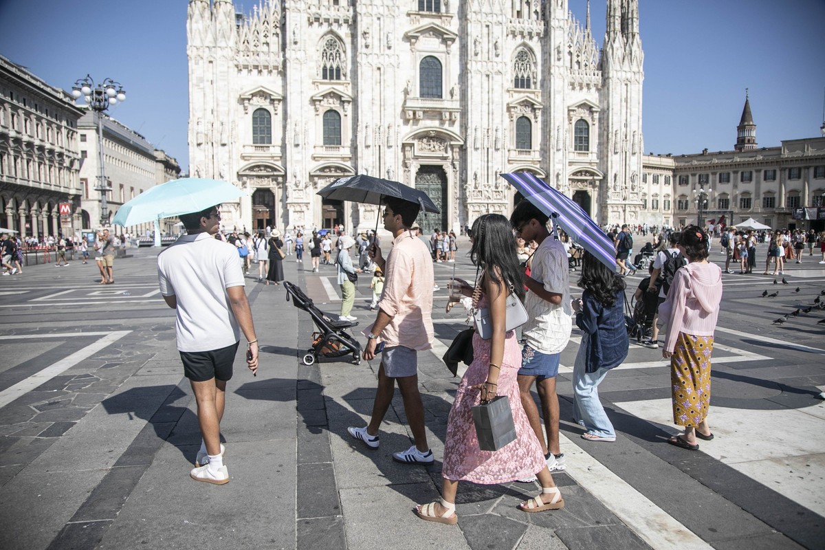09.08.2025, Italien, Mailand: Touristen gehen in der historischen Altstadt bei Hitze mit Regenschirmen gegen die sengende Sonne vor der Kathedrale. Foto: Francesco Enriquez/IPA via ZUMA Press/dpa +++ ...