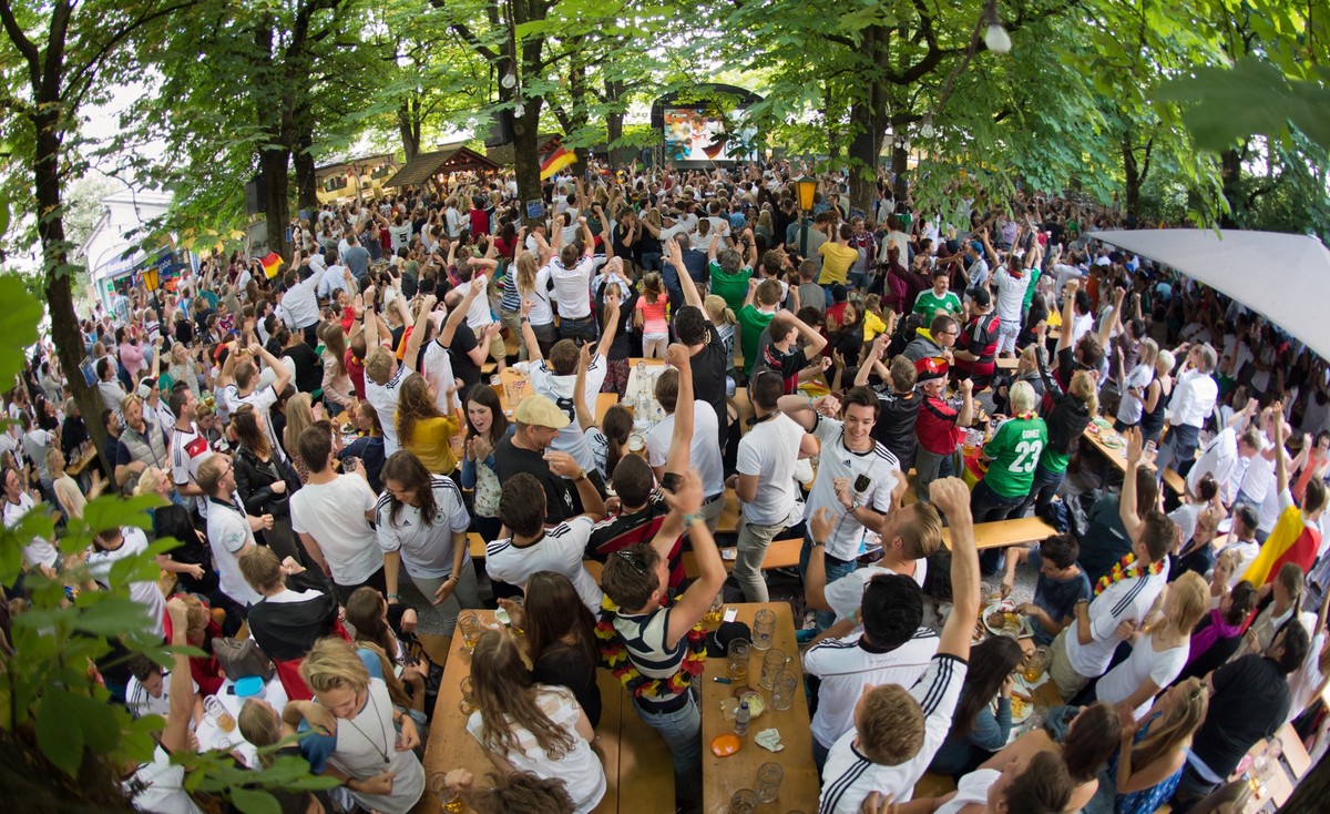 ARCHIV - 16.06.2014, Bayern, M�nchen: Fu�ballfans jubeln in einem M�nchner Biergarten w�hrend eines Spiels der deutschen Nationalmannschaft 2014. (zu dpa: �Experten sehen keinen �Jobturbo� durch Fu�ba ...