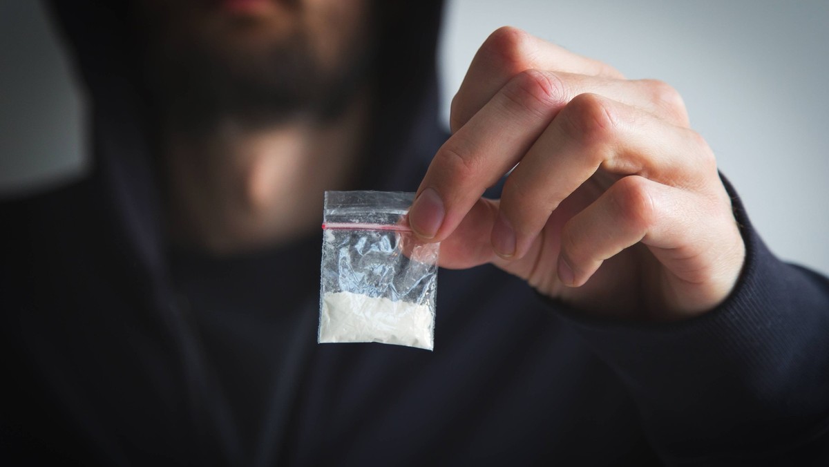 Mann in Sweatshirt und Kapuzenpulli, gesichtslos, hält kleine Tüte mit weißer Substanz - Droge, Konzept der Drogensucht, -abhängigkeit und -verteilung Mann in Sweatshirt und Kapuzenpulli, gesichtslos, ...