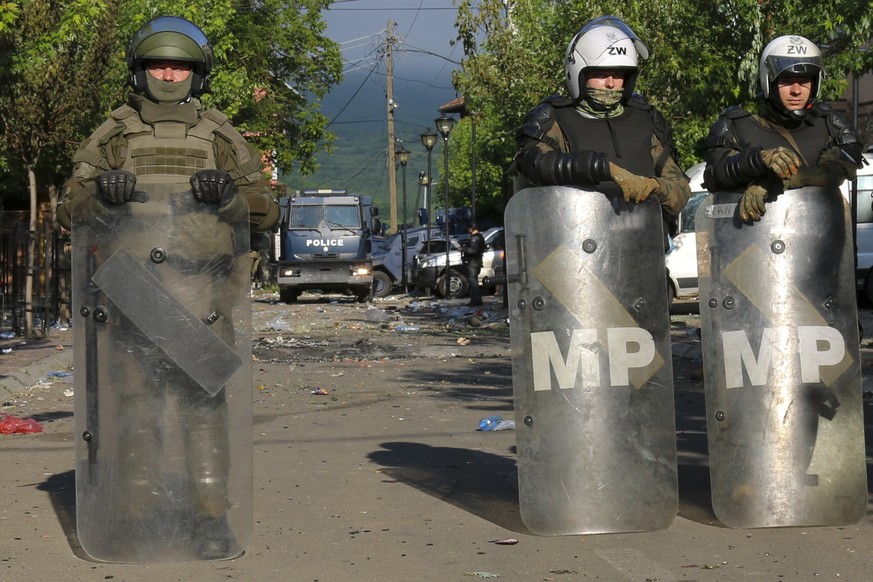 30.05.2023, Kosovo, Zvecan: KFOR-Soldaten (vorne) und Kosovo-Polizisten bewachen ein städtisches Gebäude nach den gestrigen Zusammenstößen zwischen ethnischen Serben und Truppen der NATO-geführten KFO ...