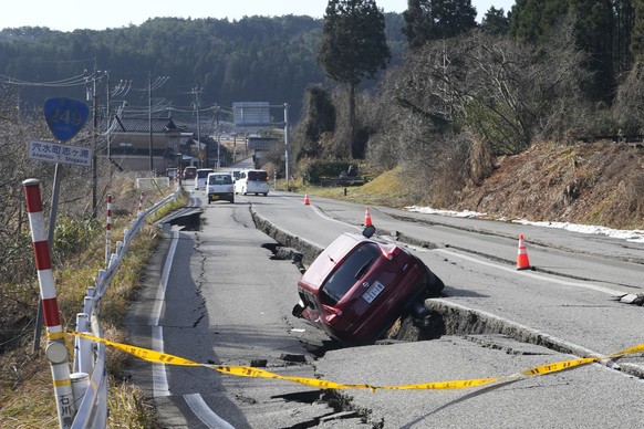 A car is trapped at a partially collapsed road caused by a powerful earthquake near Anamizu Town, Ishikawa Prefecture Tuesday, Jan. 2, 2024. A series of powerful earthquakes hit western Japan, damagin ...