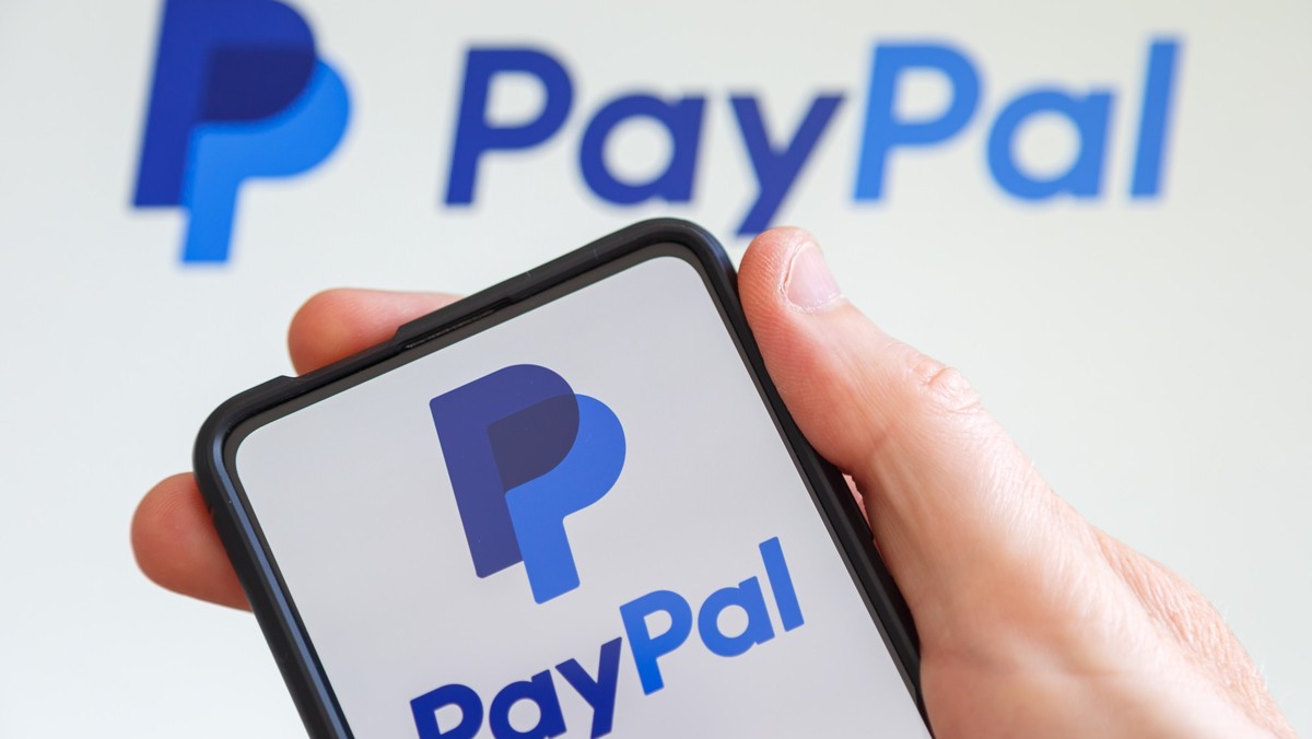 Hand holding a mobile phone with PayPal logo of the online payments company computer screen, Stuttgart, Germany - July 20, 2023: Hand holding a mobile phone with PayPal logo of the online payments com ...