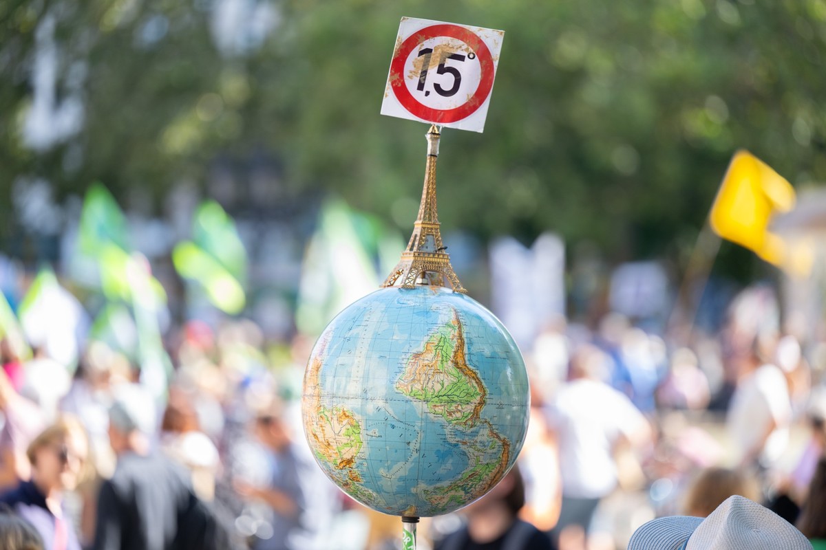 ARCHIV - 15.09.2023, Hessen, Frankfurt/Main: Einen Globus mit einem Miniatur-Eiffelturm und dem 1,5-Grad Ziel des Pariser Klimaschutzabkommens trägt ein Mann auf der Demonstration vor der Alten Oper i ...