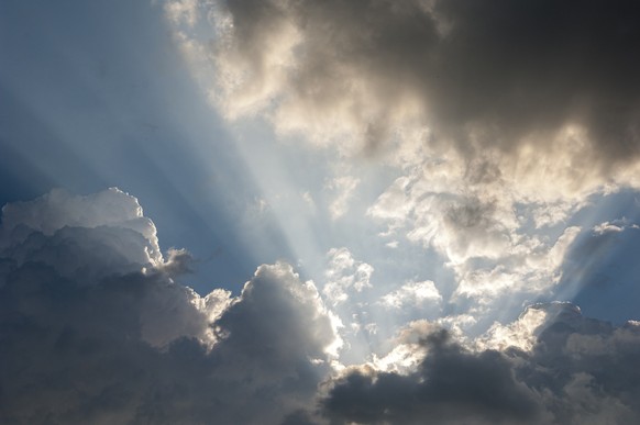 Sunbeams of the obscured sun make their way through the cloud cover