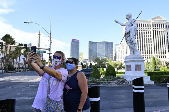 June 25, 2020 - Las Vegas, Nevada, U.S. - Tourists wearing face masks take a selfie in front of a statue of Julius Caesar at Caesars Palace along the Las Vegas Strip wearing a face mask amid the sprea ...