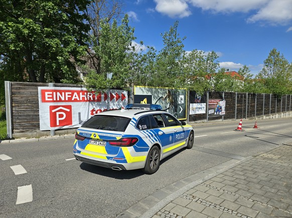 04.05.2024, Bayern, Regensburg: Ein Polizeiauto steht in der Zufahrt zur Tiefgarage eines Baumarkts, wo am Vormittag die Leiche einer Frau im Kofferraum eines Autos gefunden worden ist. Die Polizei er ...