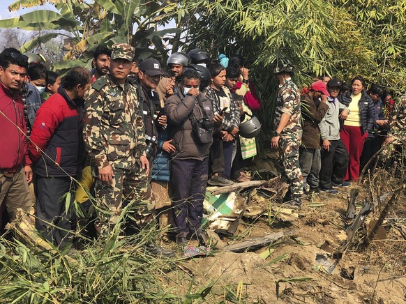 Locals watch the wreckage of a passenger plane in Pokhara, Nepal, Sunday, Jan.15, 2023. A passenger plane with 72 people on board has crashed near Pokhara International Airport in Nepal, the daily new ...