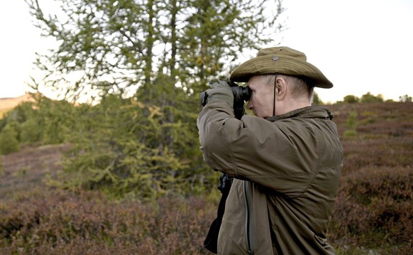 STYLELOCATIONRussian President Vladimir Putin looks through a pair of binoculars during a short vacation with Defense Minister Sergei Shoigu to fish and hike early September shown in images released S ...