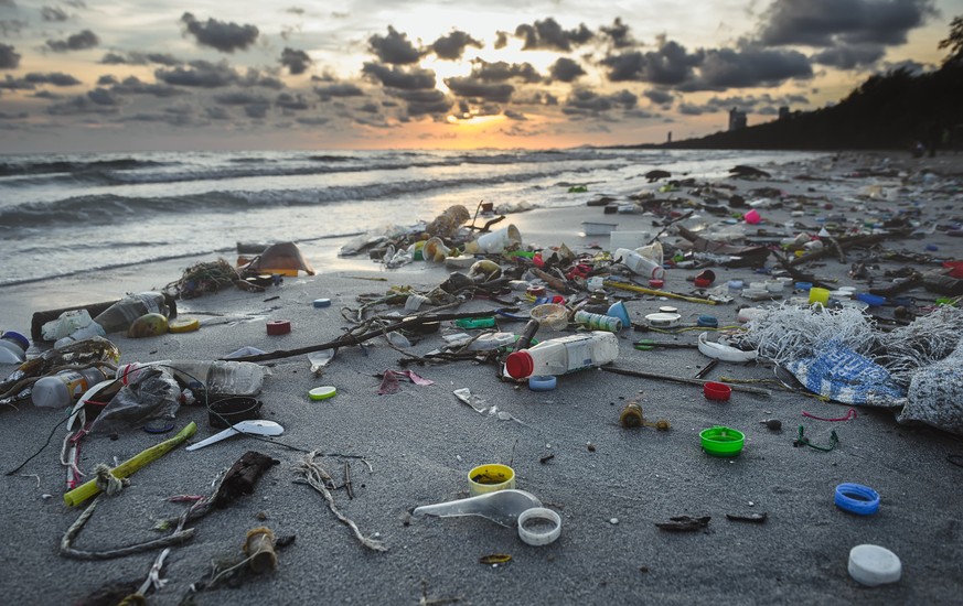 Dirty beach environment from plastic garbage with outdoor low lighting.