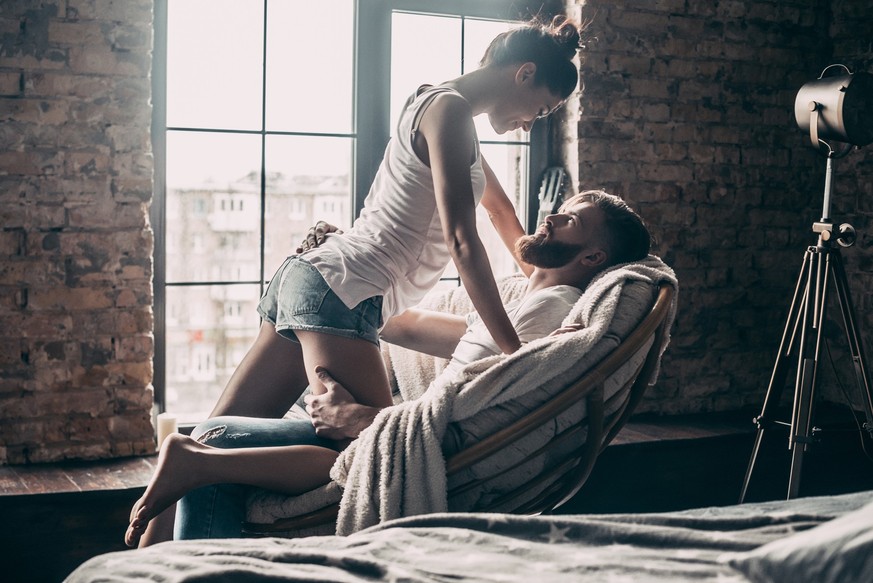 Young passionate couple looking on each other while spending free time at home