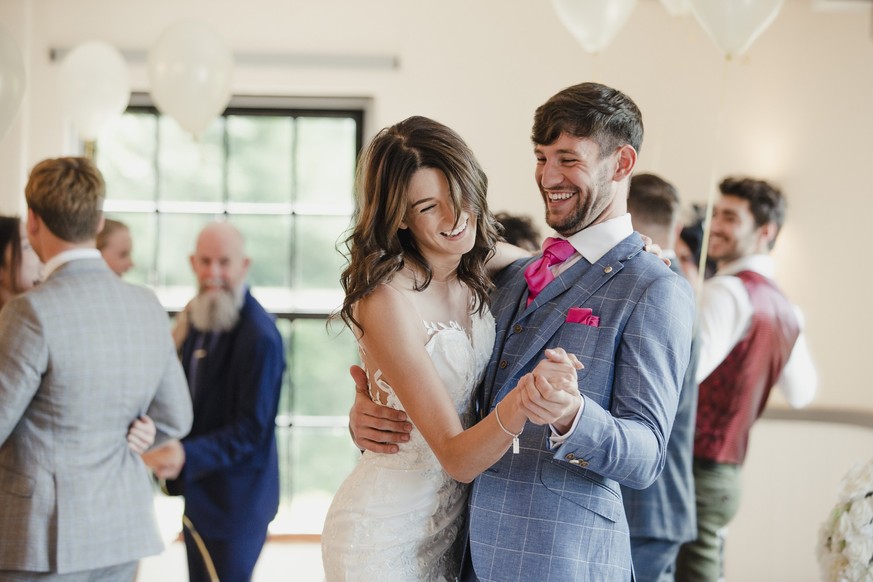 Newly wed couple are dancing together on their wedding day with all of their guests.