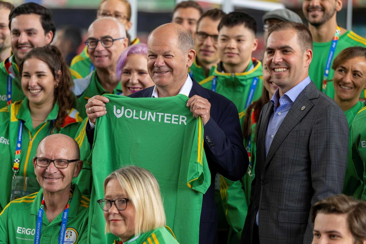 Bundeskanzler Olaf Scholz zwischen Volunteers und dem EM-Turnierdirektor Lahm.