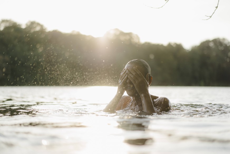 Woman in a lake at sunset splashing with water model released Symbolfoto property released PUBLICATIONxINxGERxSUIxAUTxHUNxONLY KNSF05169